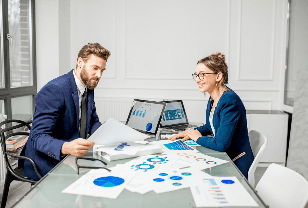Franchise business owner analyzing financial reports, using accounting software, and discussing cost strategies with an advisor.